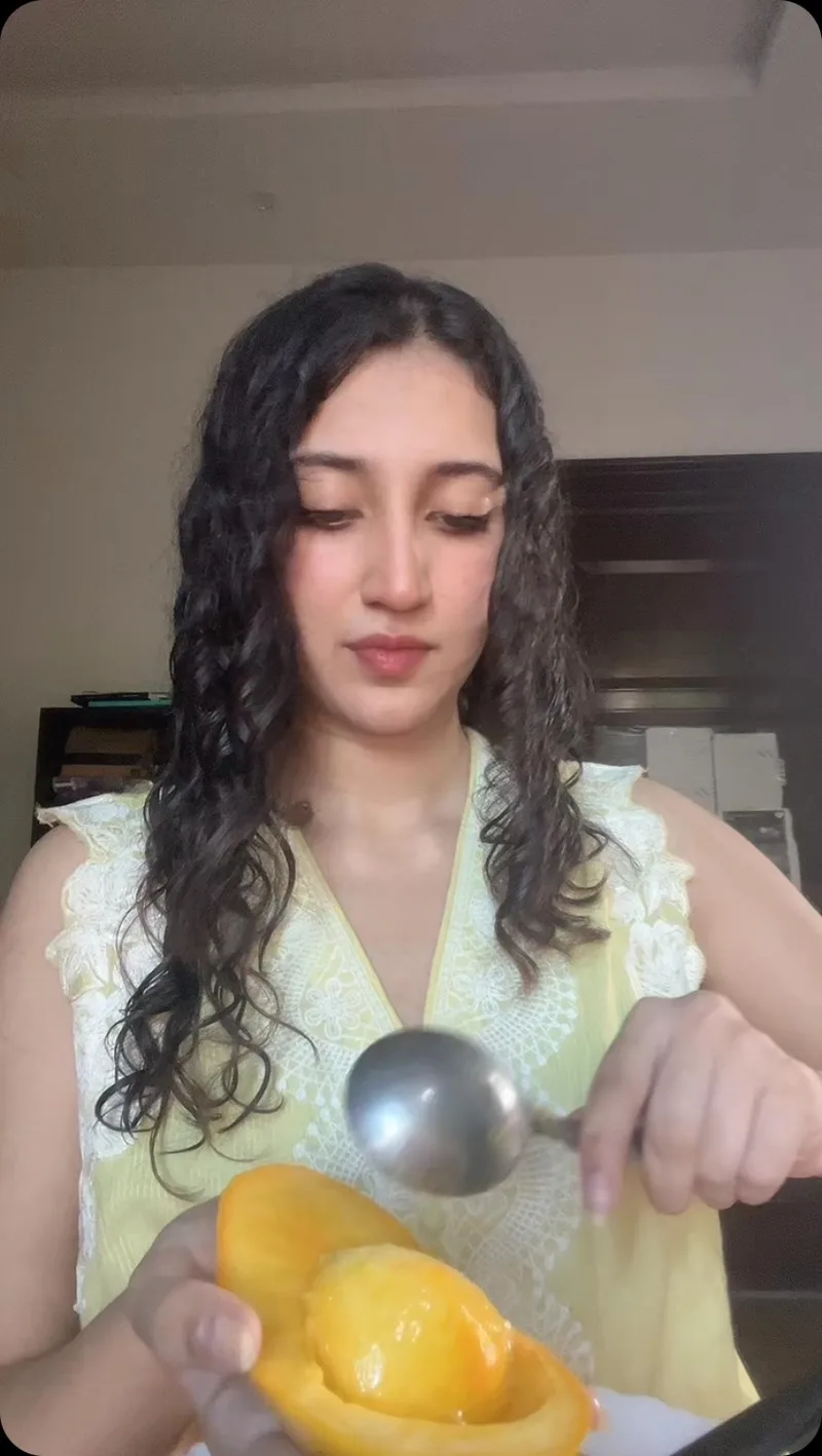 Scooping golden ripe Sindhri mango flesh with spoon - naturally ripened Pakistani mango